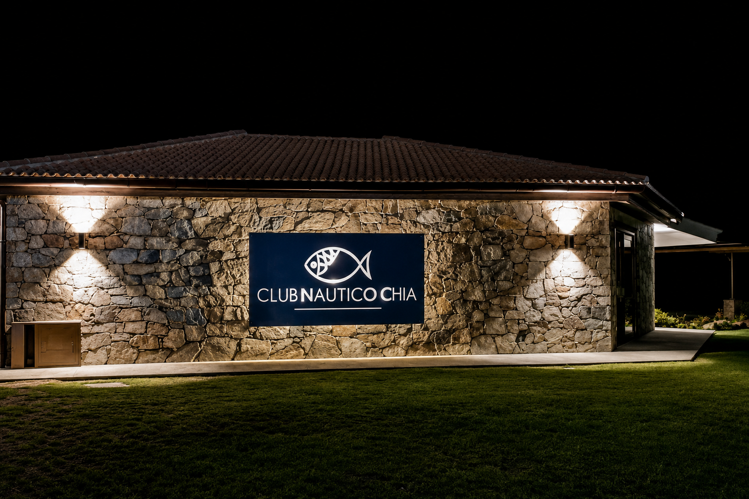 Insegna in pietra del Club Nautico Chia illuminata di notte